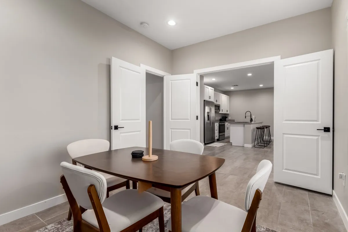 A warm dining area centered around a wooden table with four chairs, located just outside the kitchen doorway. The intimate setup is ideal for family dinners, casual brunches, or celebratory toasts, with a cozy, welcoming atmosphere.