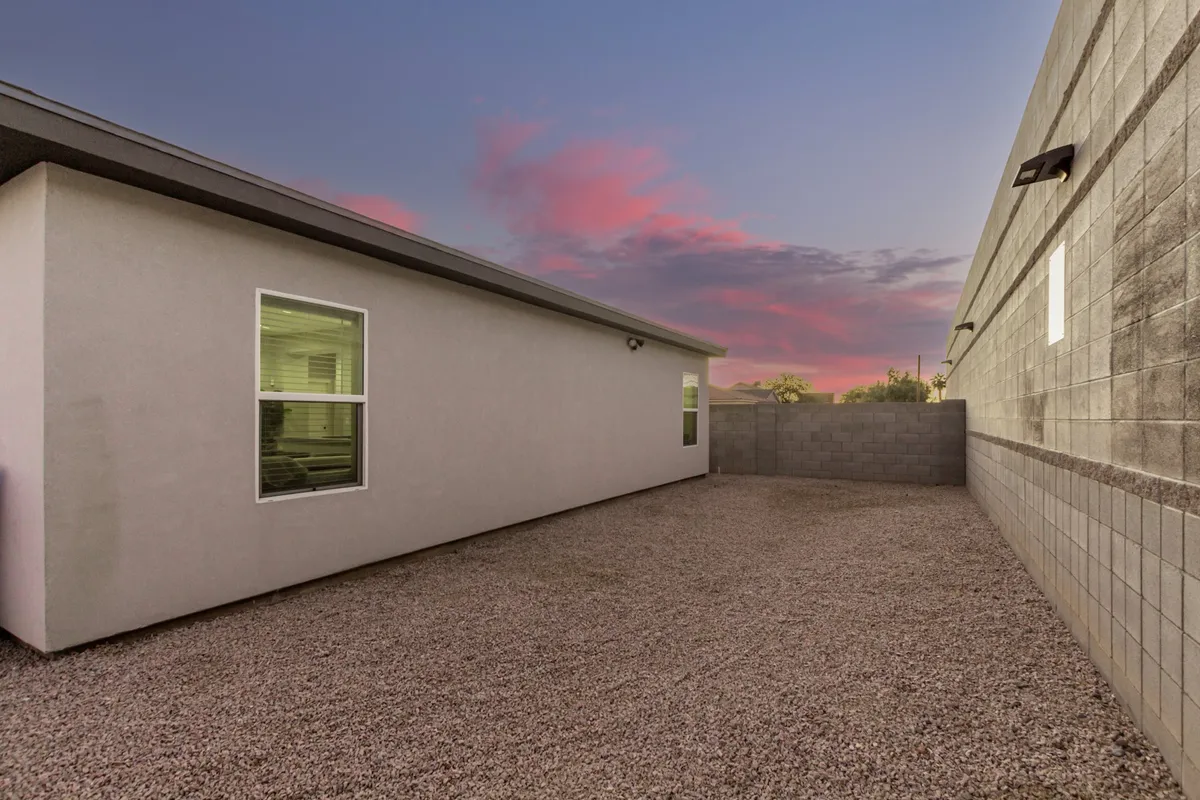 A wide exterior view of the home, showcasing its welcoming facade, a low wall, and a serene sky above. The scene suggests opportunities for outdoor relaxation and social gatherings, with the home positioned as a peaceful retreat in central Phoenix.