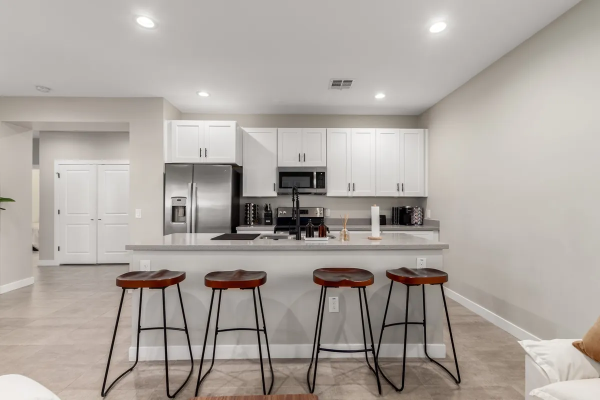 This image spotlights a welcoming kitchen featuring a large island with stools, sleek modern appliances, and open space ideal for gathering and entertaining. The layout encourages socializing and hosting—perfect for group activities like cooking together or sharing a casual meal after a night on the town.