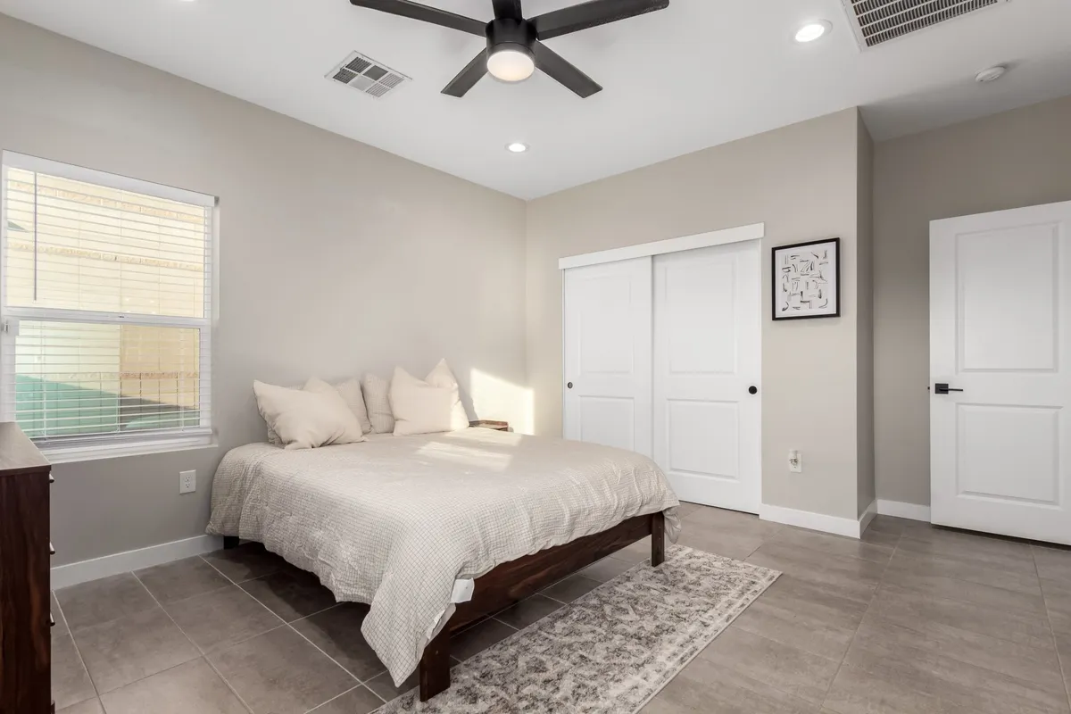 A cozy bedroom featuring a neatly made bed, a window that lets in natural light, a dresser, and thoughtfully placed artwork. The space feels warm and welcoming, perfect for relaxation or a good night's sleep.