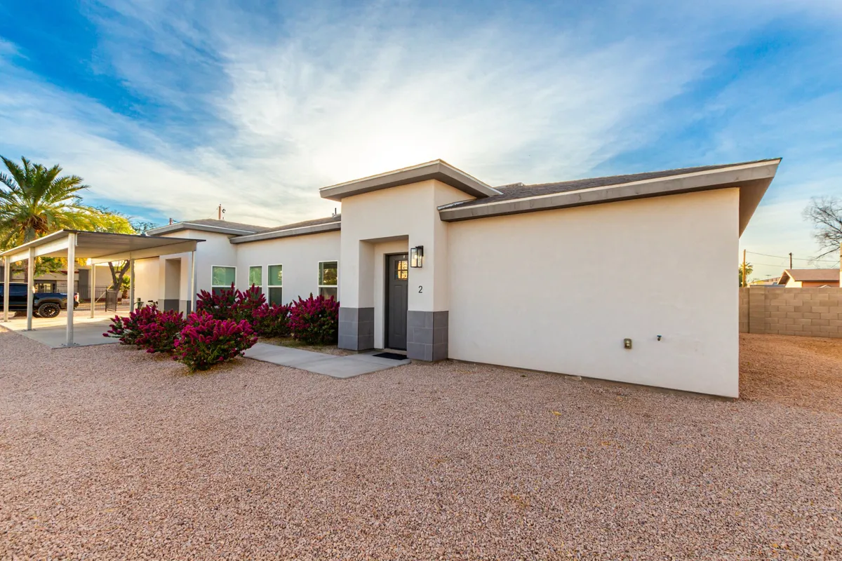 The hero image shows the inviting front entrance of a single-family home, surrounded by neatly landscaped shrubs, a tidy gravel driveway, and a welcoming porch. The setting is bathed in warm sunset light, creating a tranquil and friendly atmosphere ideal for relaxing and connecting with neighbors or enjoying a peaceful moment with a morning coffee.